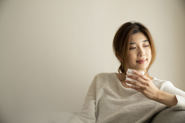 部屋で水割りを飲む女性
