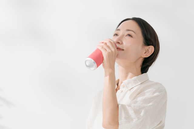 缶のドリンクを飲む女性
